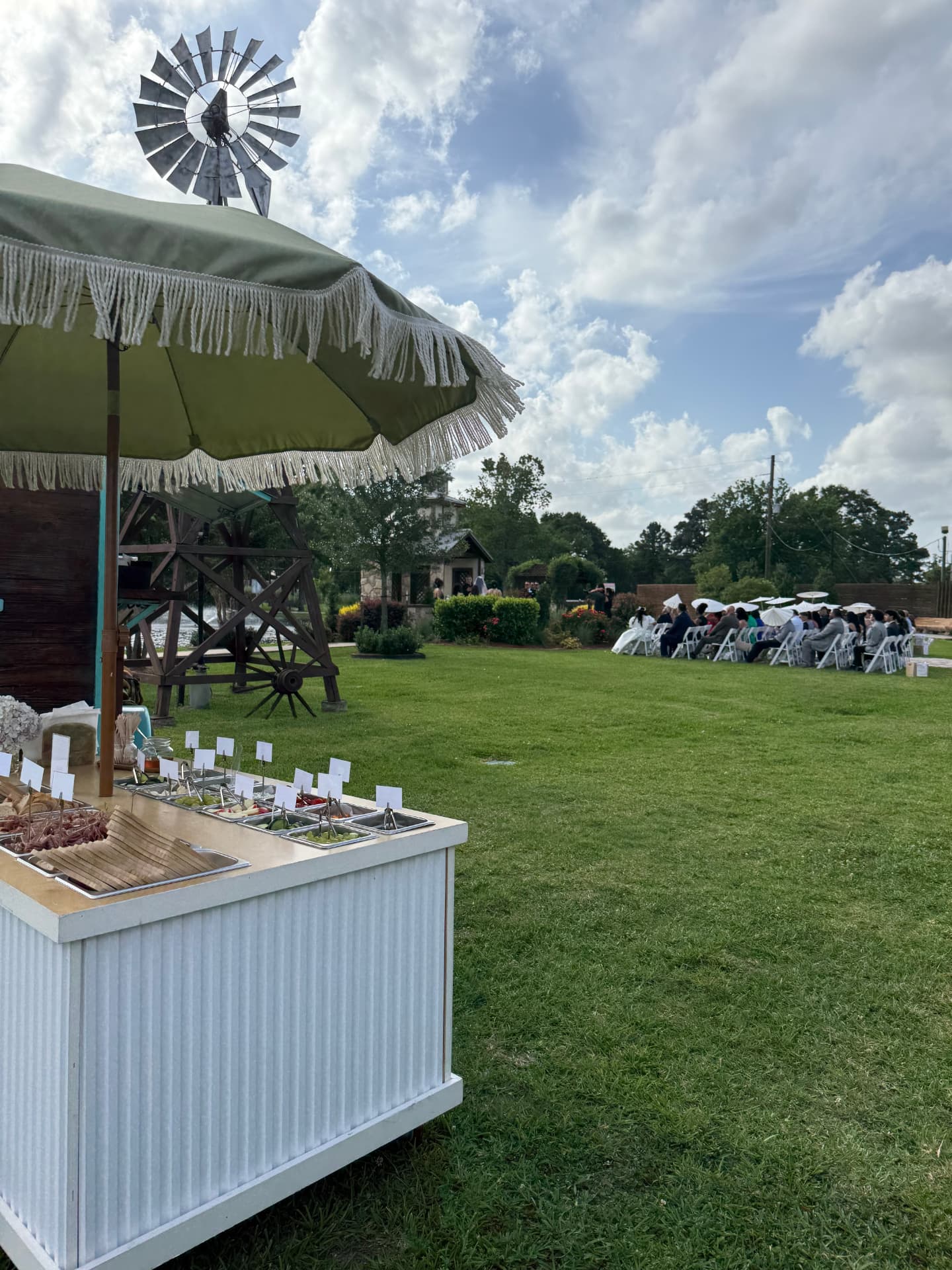 The charcuterie cart on a garden lawn during an outdoor wedding ceremony