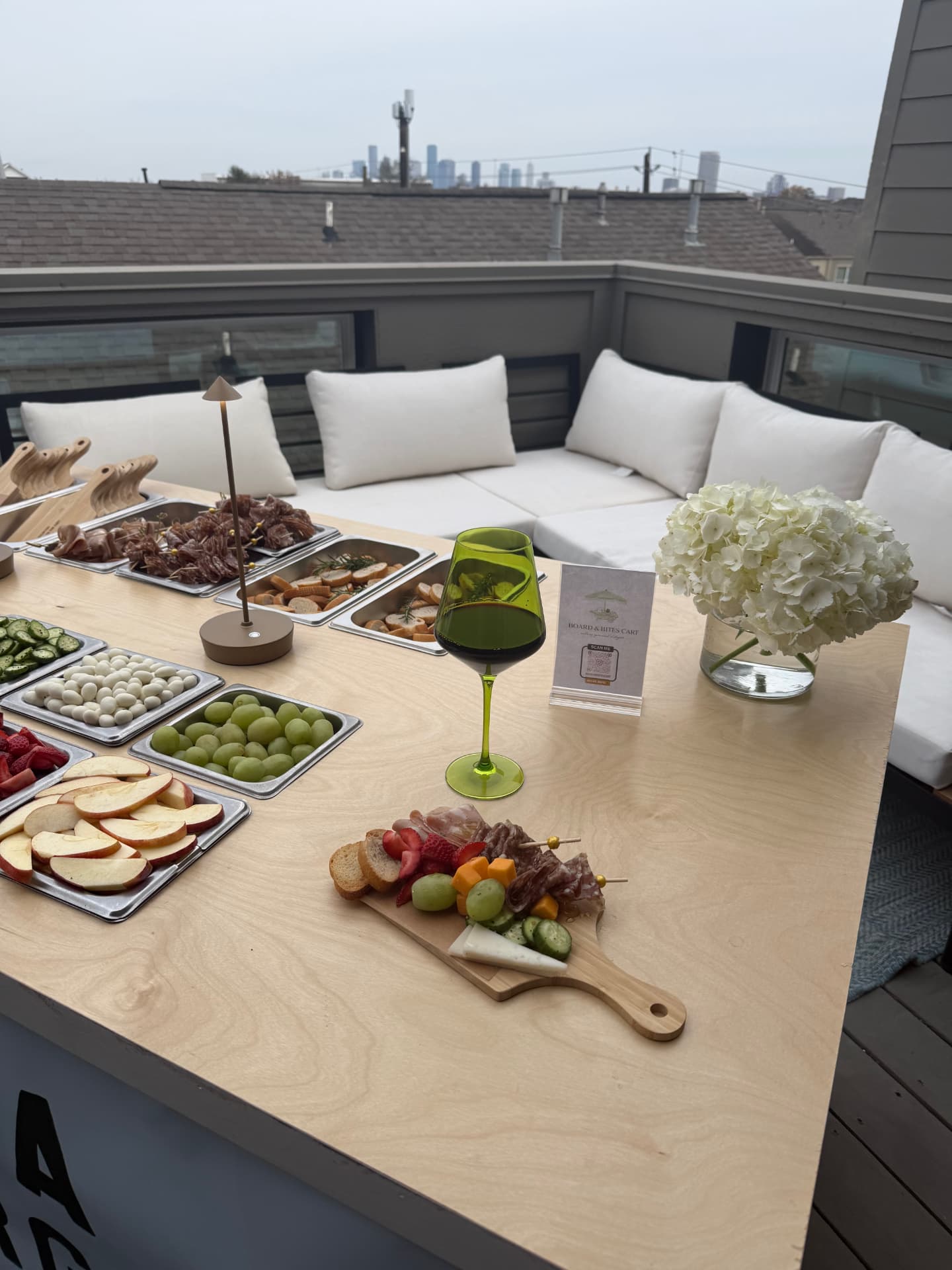 Rooftop charcuterie spread with meats, cheeses, fruit and wine